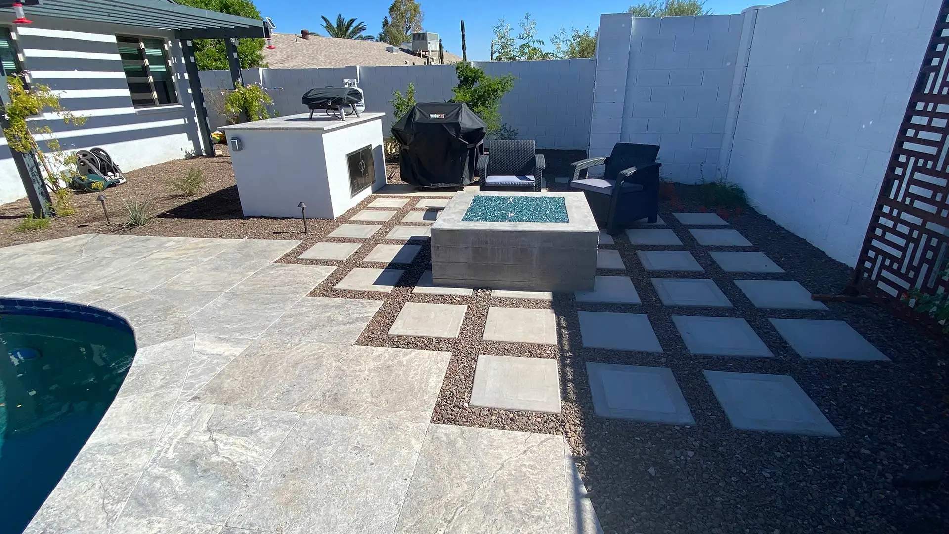 Patio with square pavers installed beside outdoor kitchen and fire pit in Glendale, AZ.